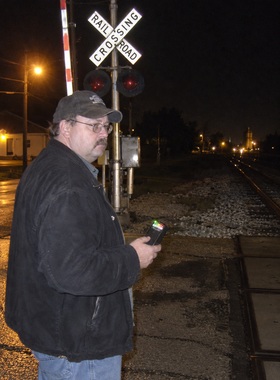 Dale Hutchins at Washington Street grade crossing Grayslake Illinois at night holding EMF meter