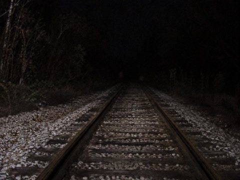 Night photograph looking north along Metra NCS tracks Washington Street Grayslake Illinois faint standing figure visible between rails